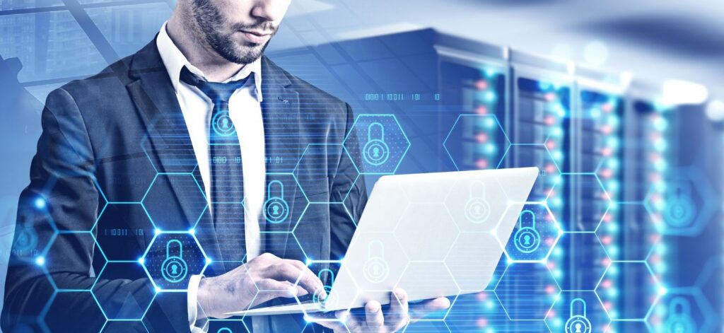 A man in a suit holding a laptop in front of a server, representing fractional CTO services.